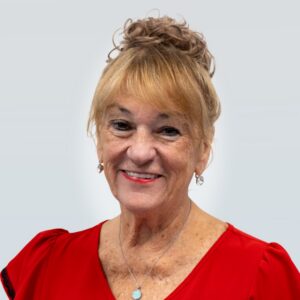 Diane Delaney's headshot, wearing a red blouse, with her hair up in a bun