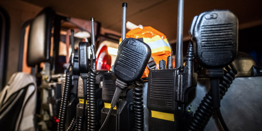 First-responder radio packs lined up against a wall.
