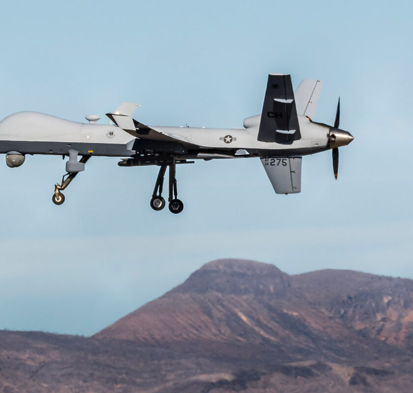 A US military drone flying over mountains.