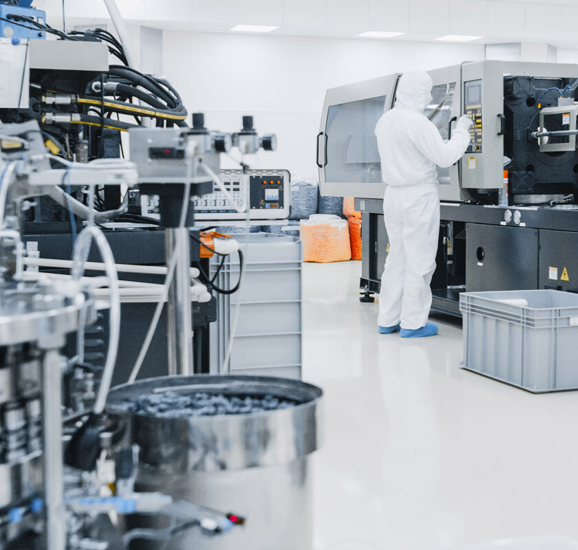 A scientist in protective gear operating a semiconductor machine.